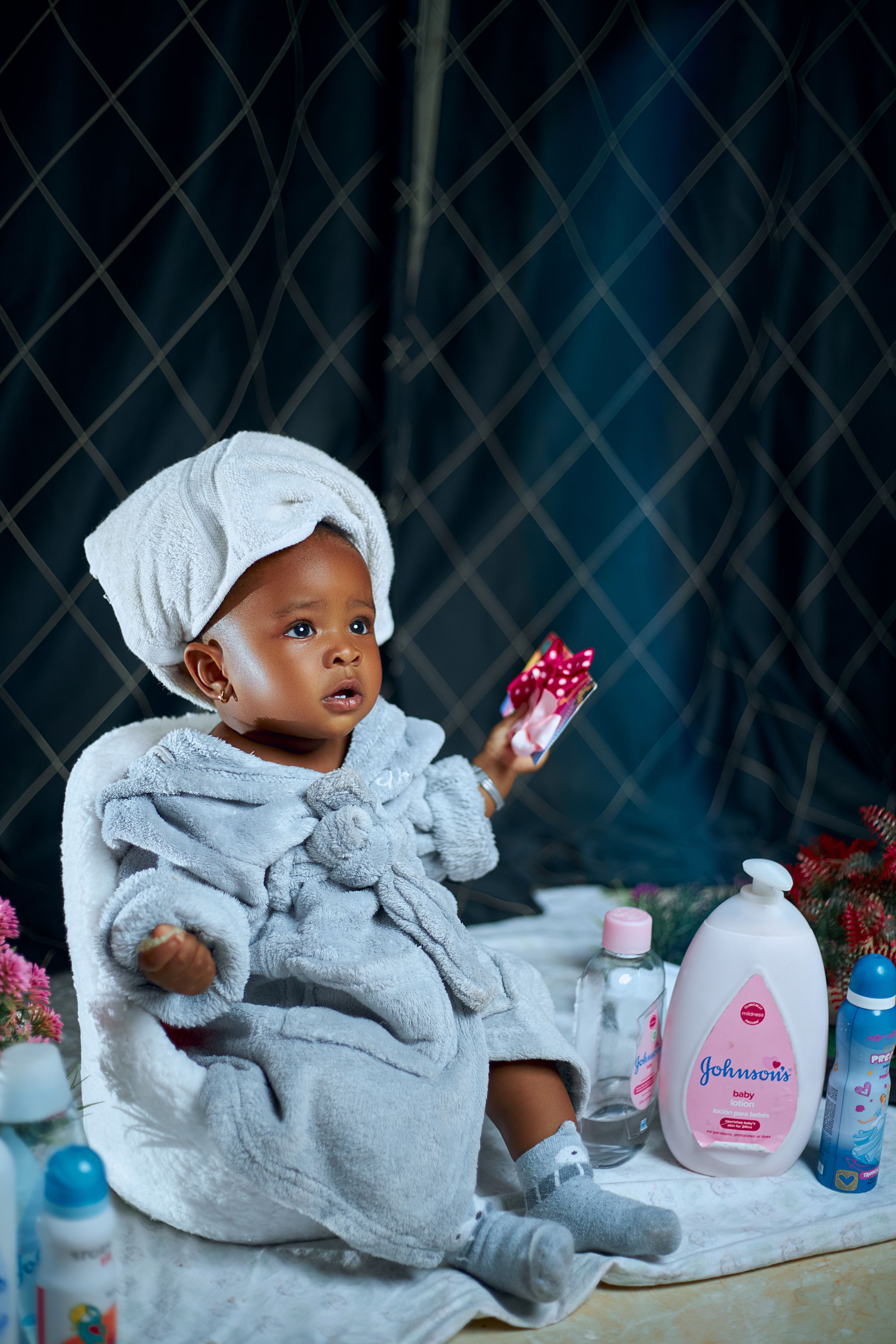 Niño en albornoz rodeado de productos de higiene